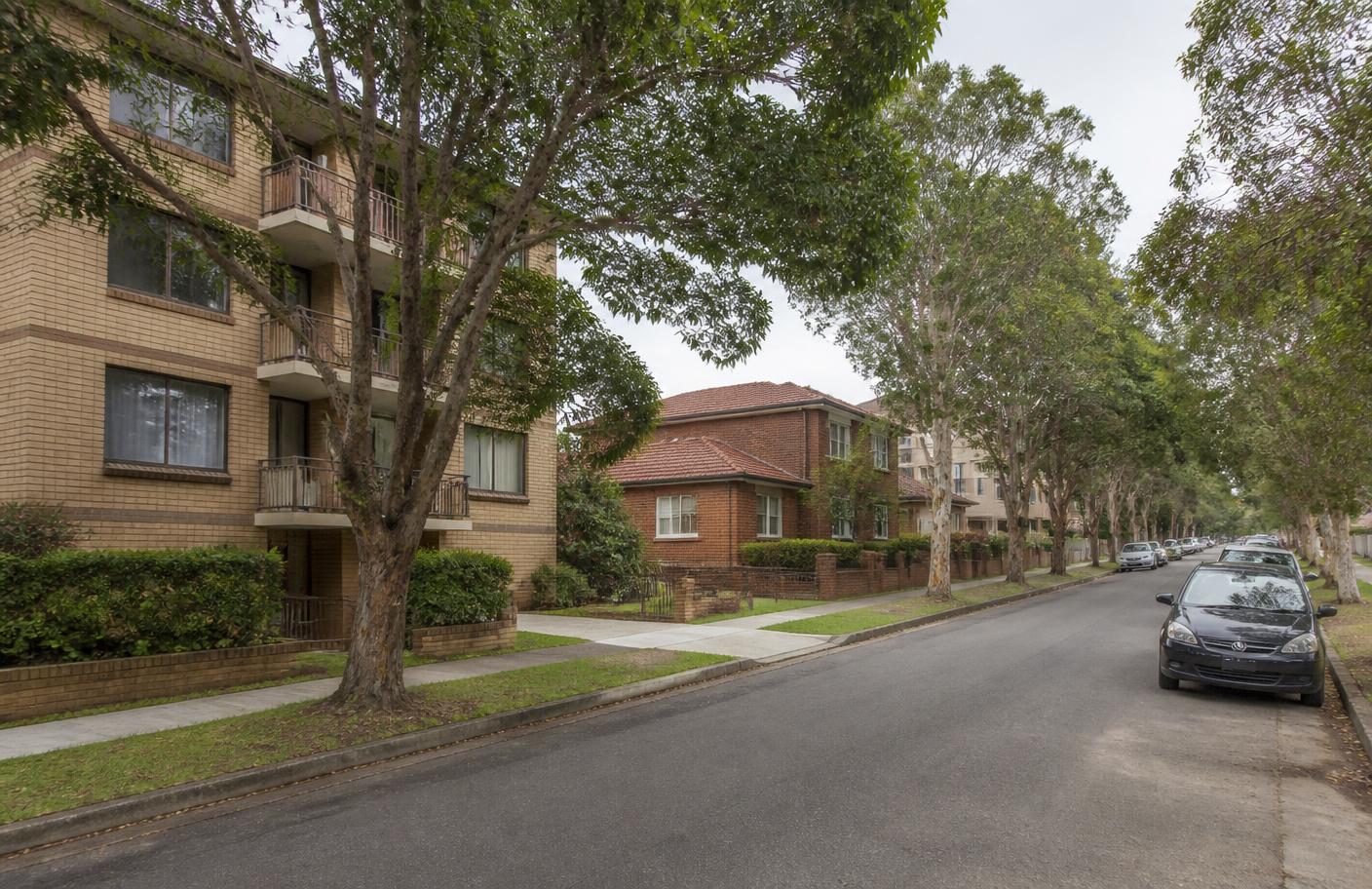 A tree-lined Bankstown street with low-rise apartments beside older brick houses